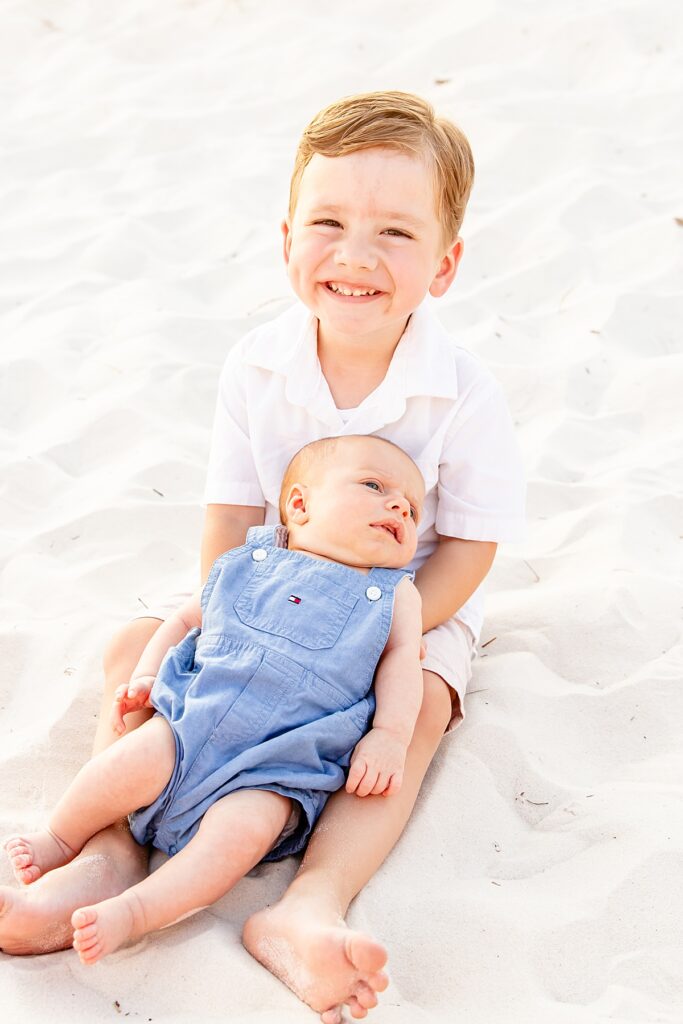 little boy holding baby on pensacola beach during extended family session