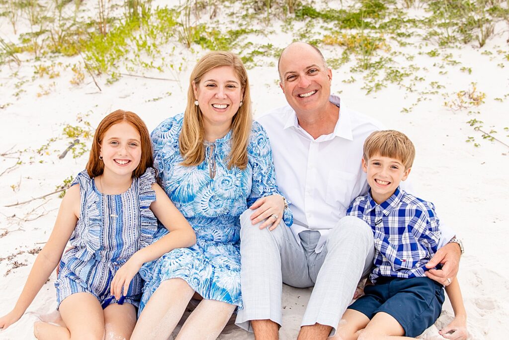 family sitting in the sad during family session on pensacola beach