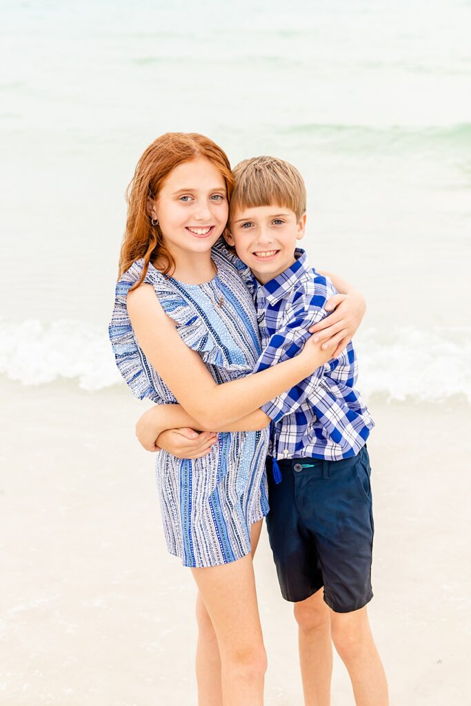 siblings hugging by the water during family session on pensacola beach