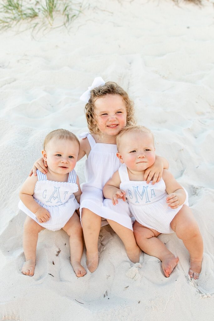 Little girl and two little boys posing in the sand