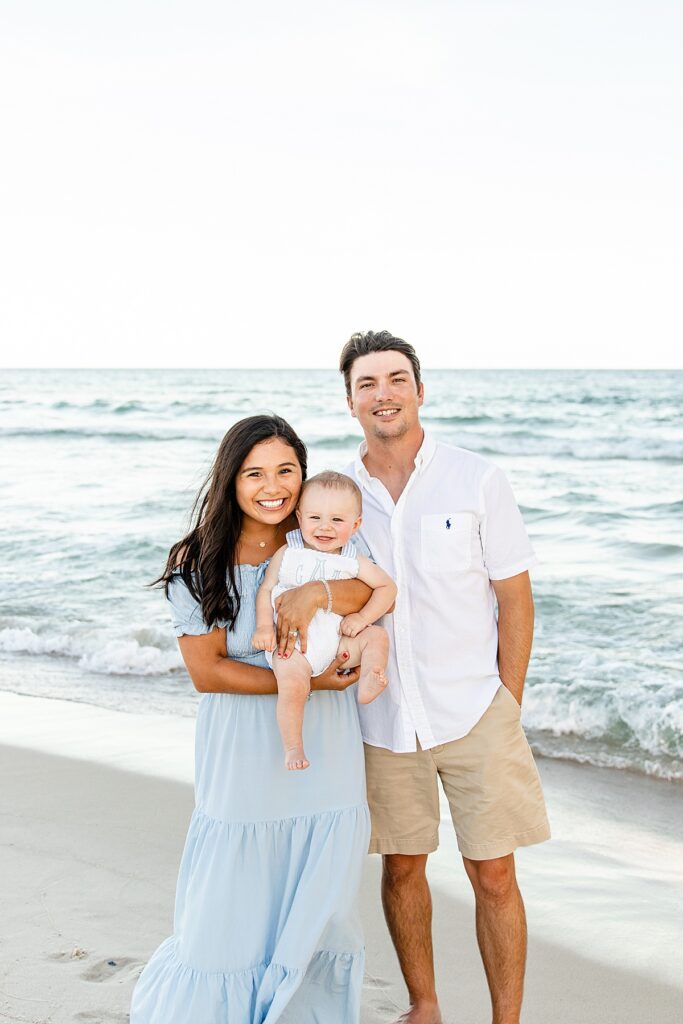 Young family holding a baby by the water in Gulf Shores, Alabama